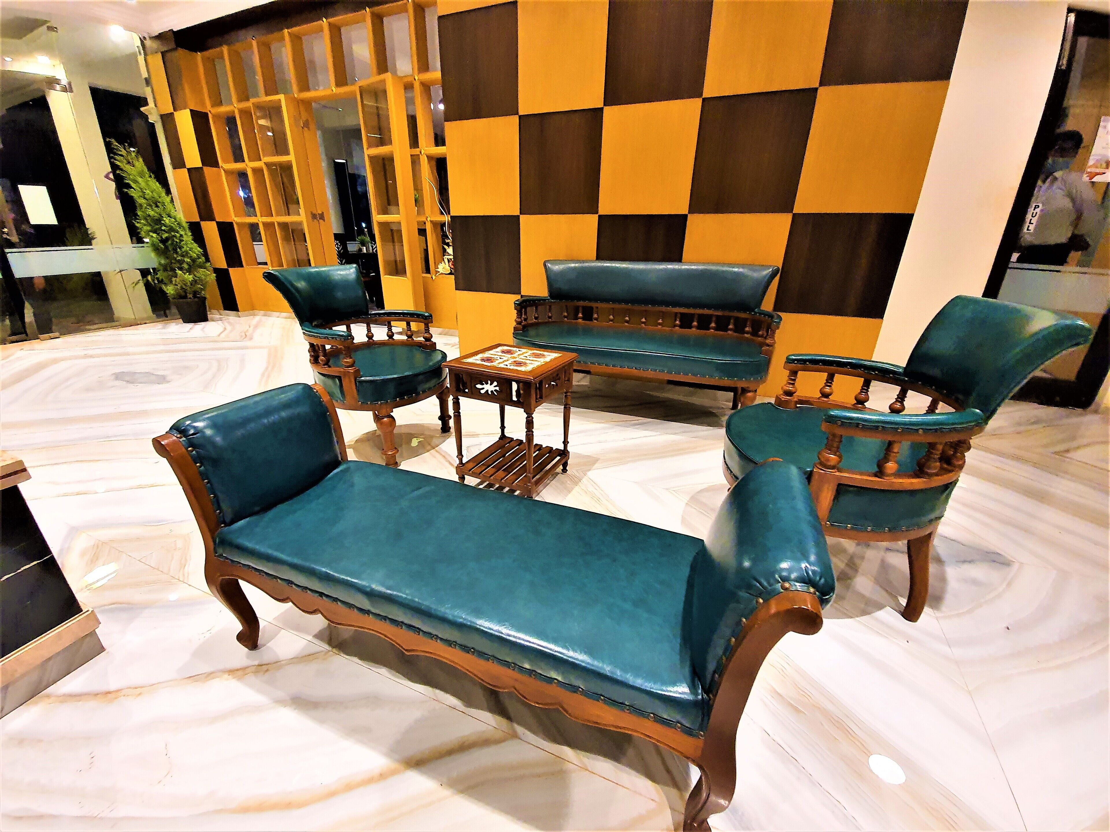 A seating area with a sofa, two armchairs, and a small table, set against a checkered wall.