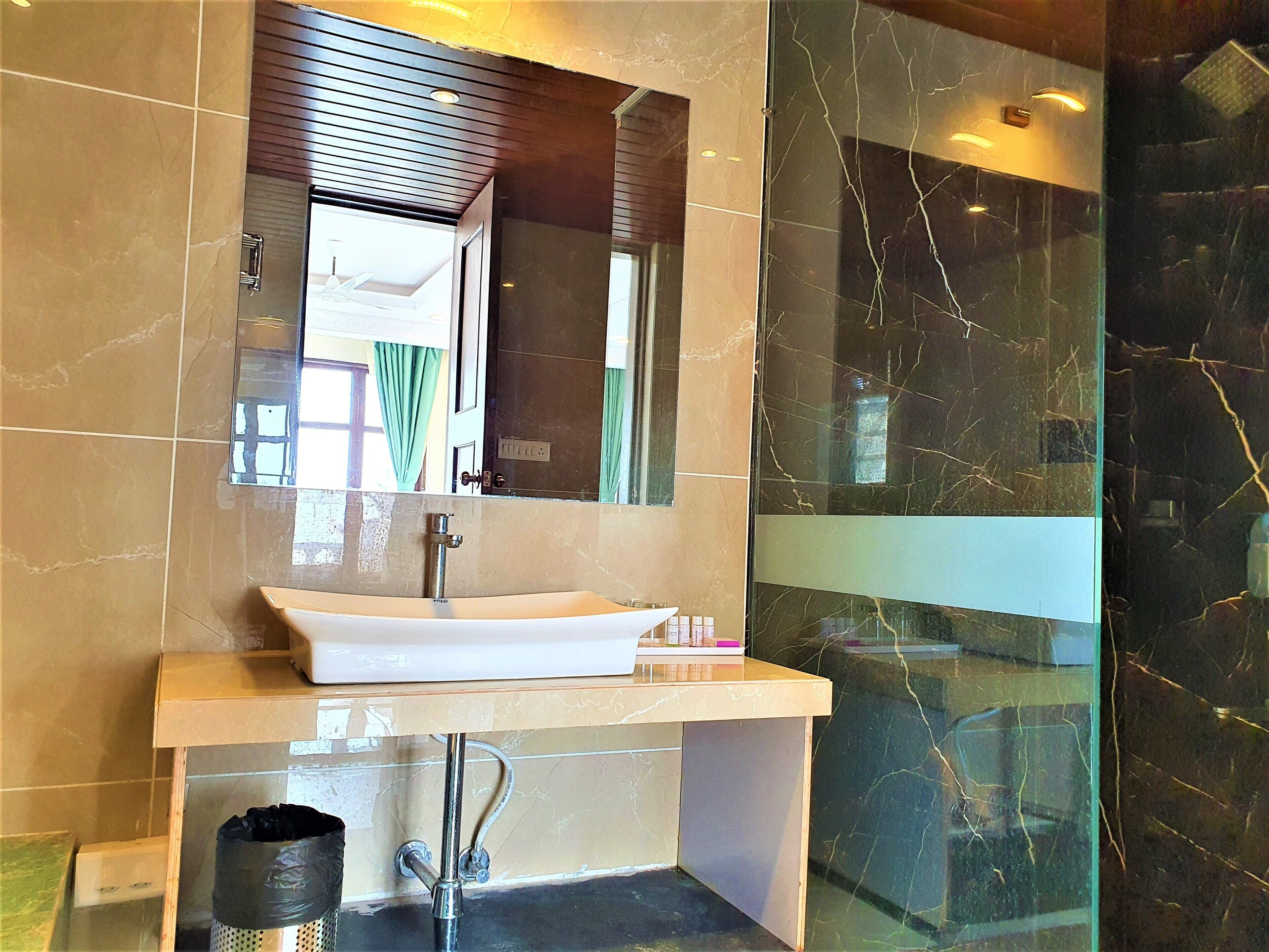 A modern bathroom with a marble vanity, a large mirror, and a glass shower enclosure.