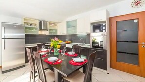 Una cocina moderna con una mesa de comedor lista para cuatro personas, equipada con refrigerador, microondas y estufa.