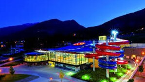 A modern building with a glass facade and a unique spiral structure with red and blue elements. - Description (Schwendau)