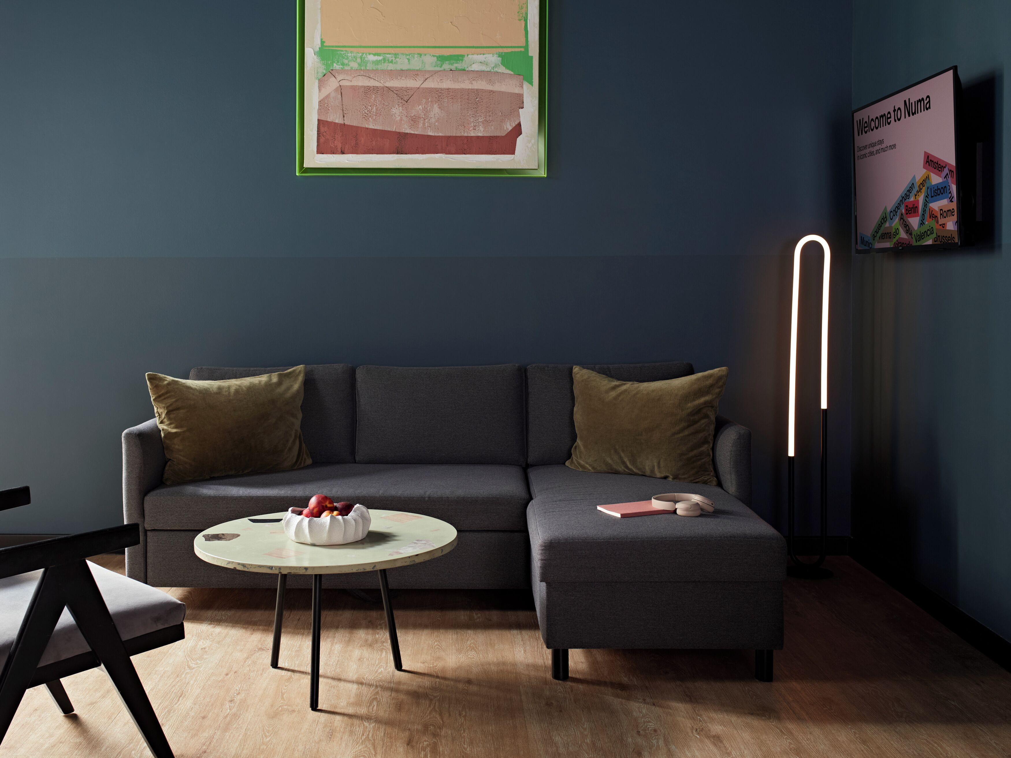 Een moderne woonkamer met een grijze bank, een ronde tafel en een vloerlamp.