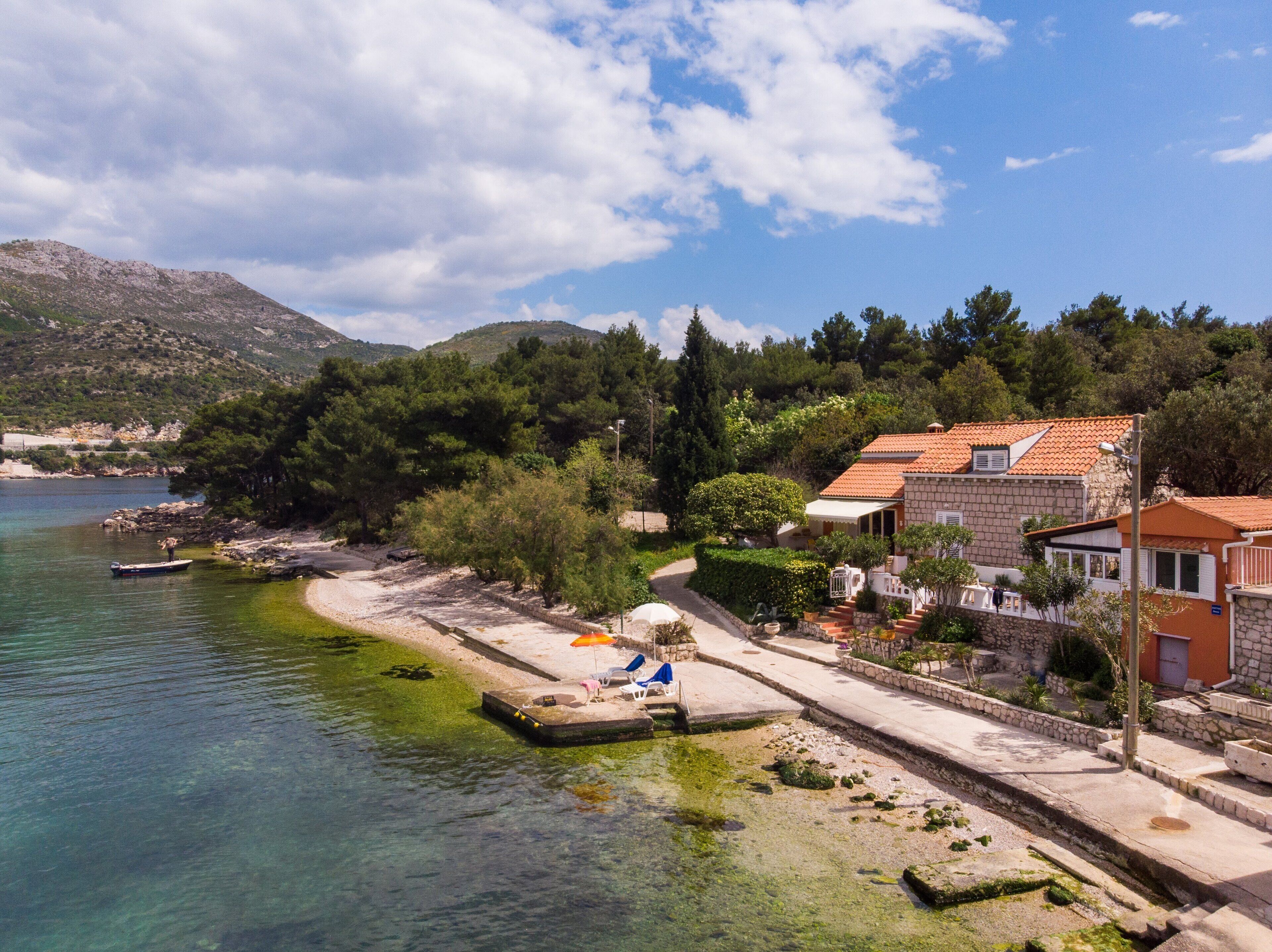 A coastal property with a stone building, a dock, and a clear view of the sea.
