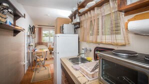 A compact kitchen with a refrigerator, microwave, sink, and stove. There is a small dining area with a table and chairs.