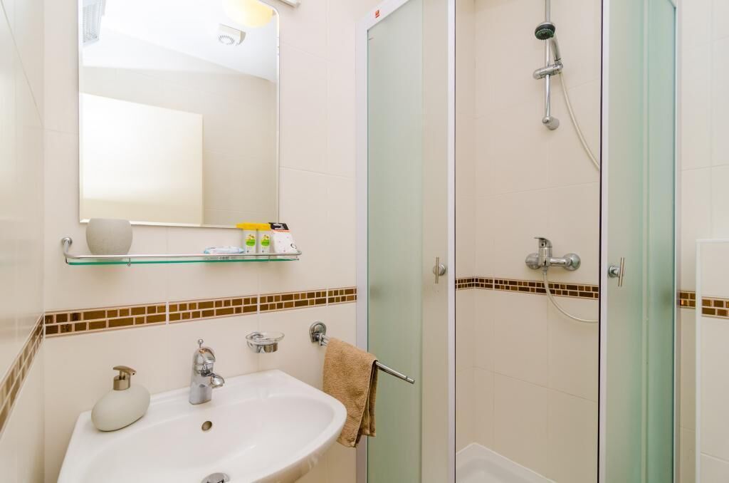 A bathroom with a sink, mirror, and glass-enclosed shower.