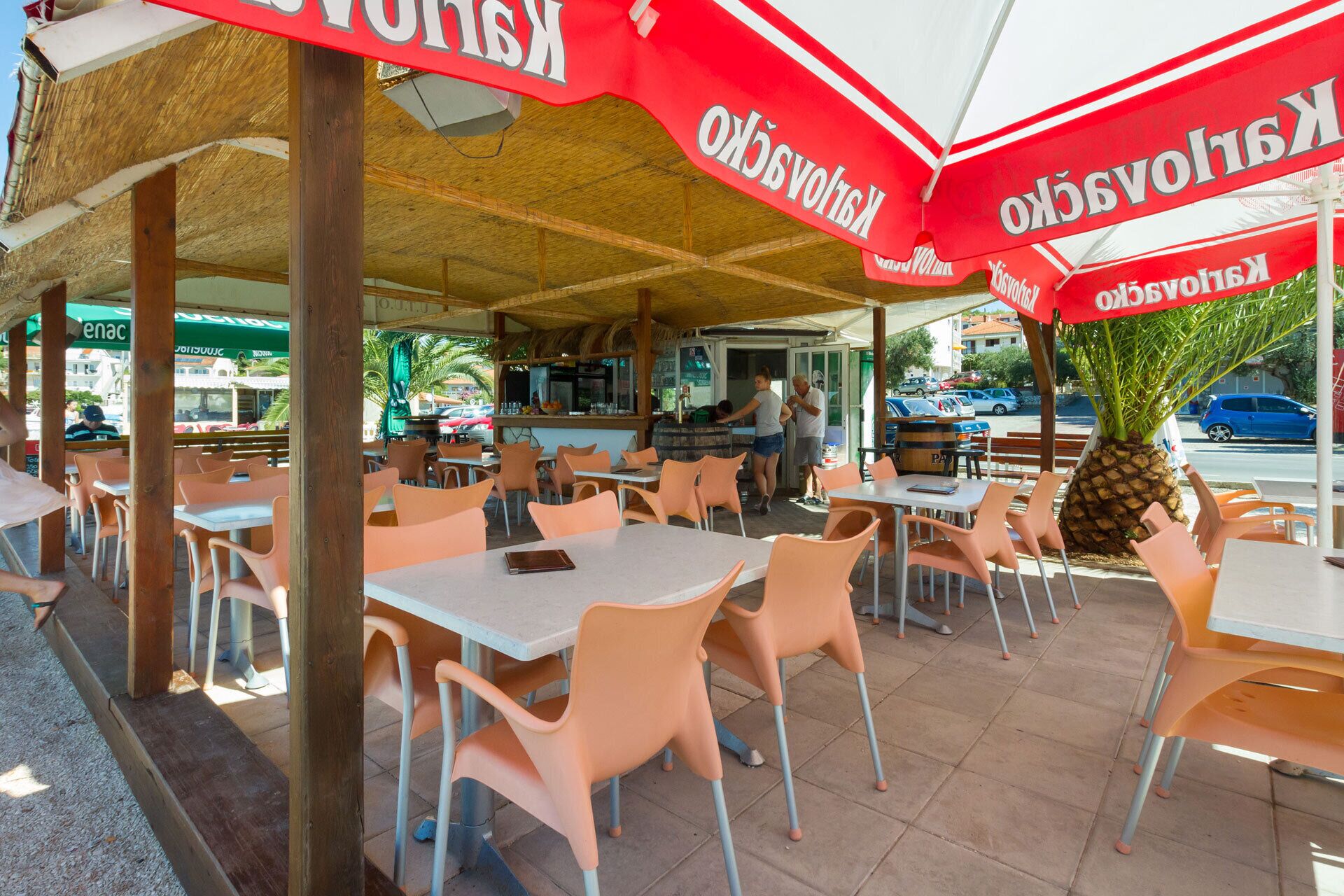 An outdoor seating area with tables and chairs, umbrellas, and a pineapple decoration.