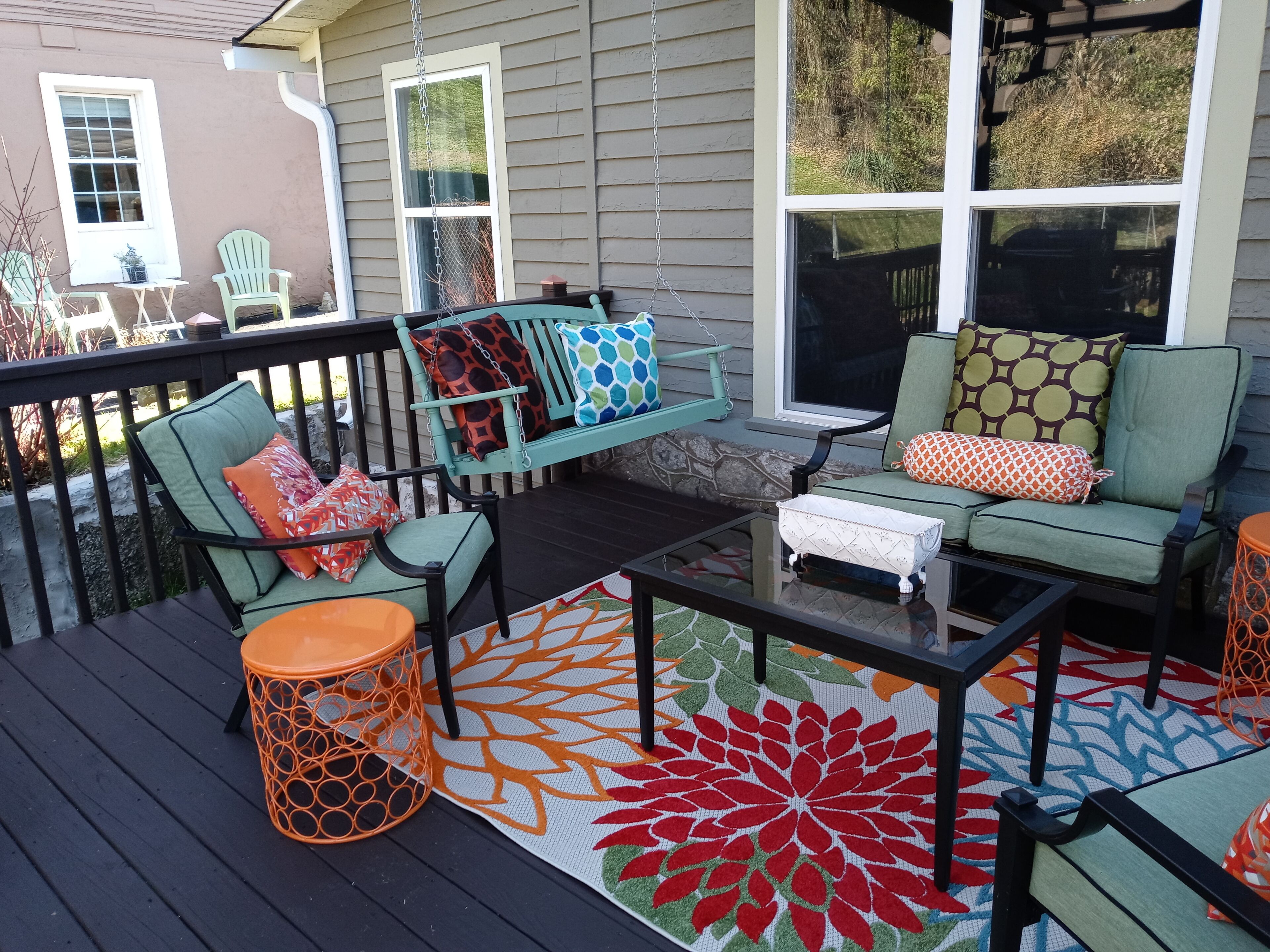 A deck with outdoor furniture, including chairs and a sofa, and a coffee table.