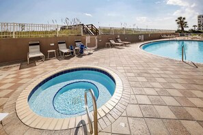 A swimming pool with a sunbathing area and a small hot tub.