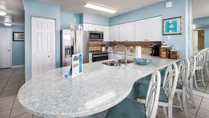 Una cocina con una isla grande, armarios blancos, un microondas y un fregadero.