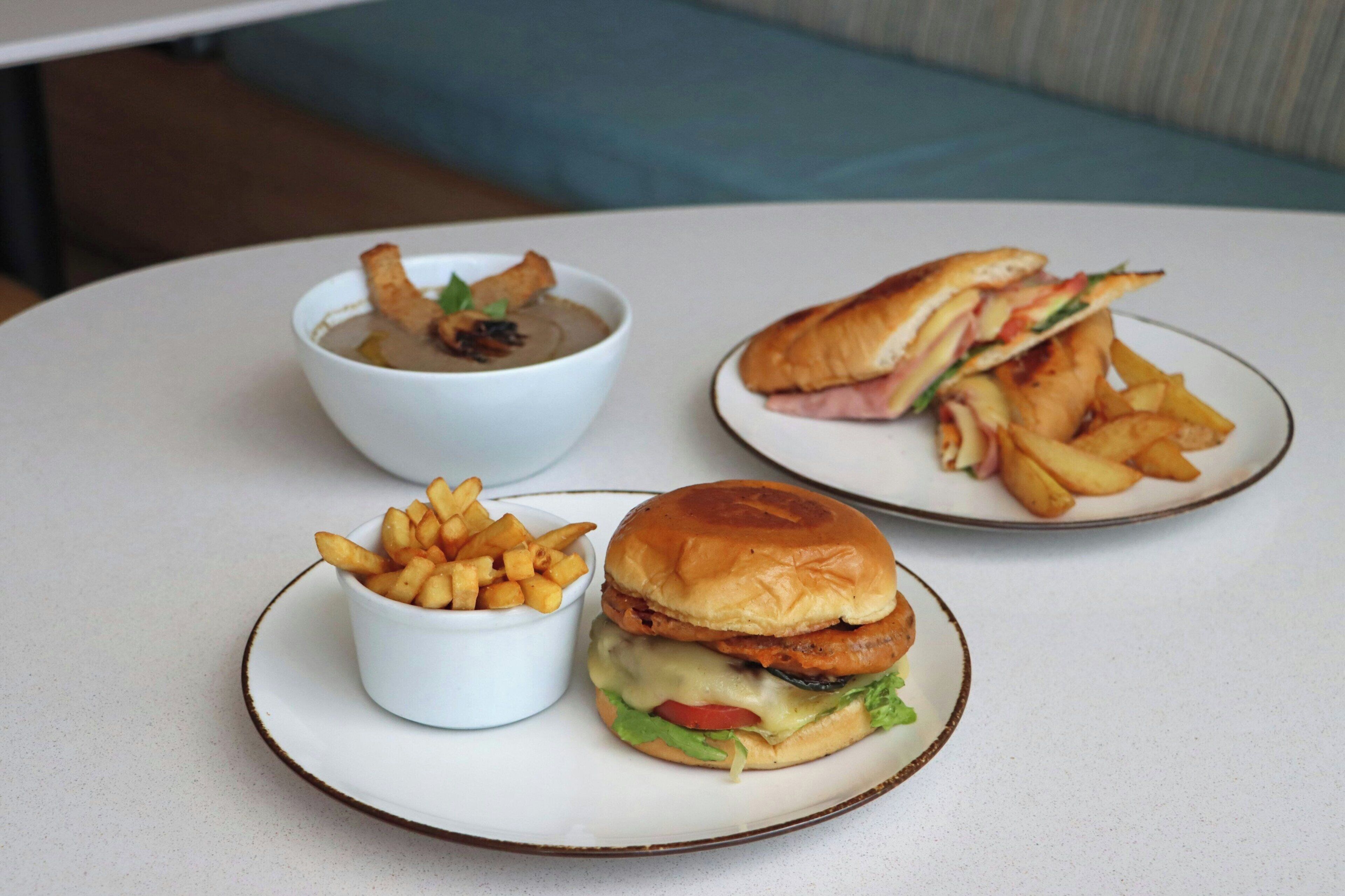 Una mesa con un sándwich, papas fritas y un tazón de sopa.