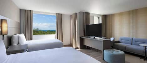 A hotel room with two beds, a TV, a sofa, and a desk.