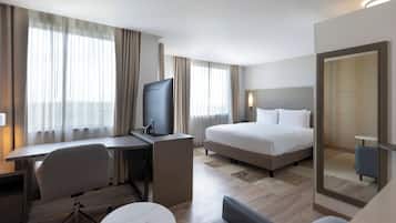 A hotel room with a bed, a desk with a chair, a television, and a small table.