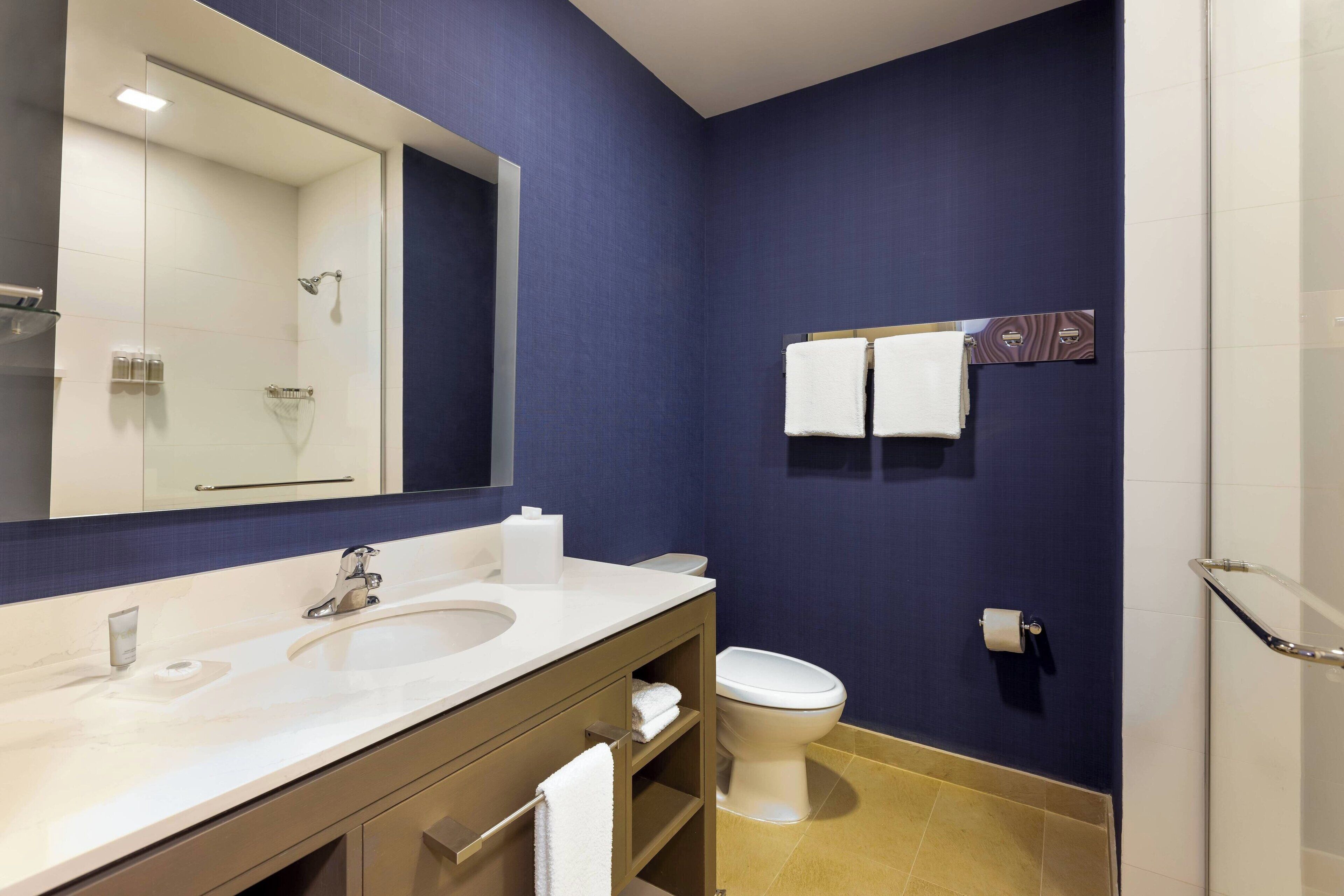 Een moderne badkamer met een grote spiegel, een wastafel, toilet en douchehoek.
