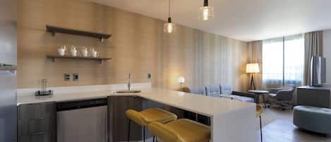 Una cucina moderna con isola centrale, sgabelli da bar e zona pranzo con divano e sedie.