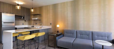 Una cucina moderna con isola centrale, sgabelli da bar, un divano e un piccolo tavolo.