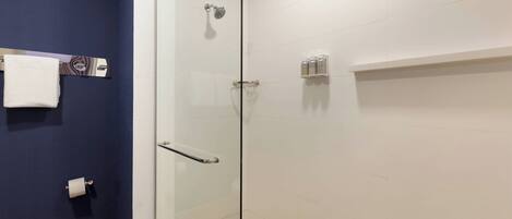Un baño moderno con cabina de ducha de vidrio, bañera blanca y una pared de acento azul.