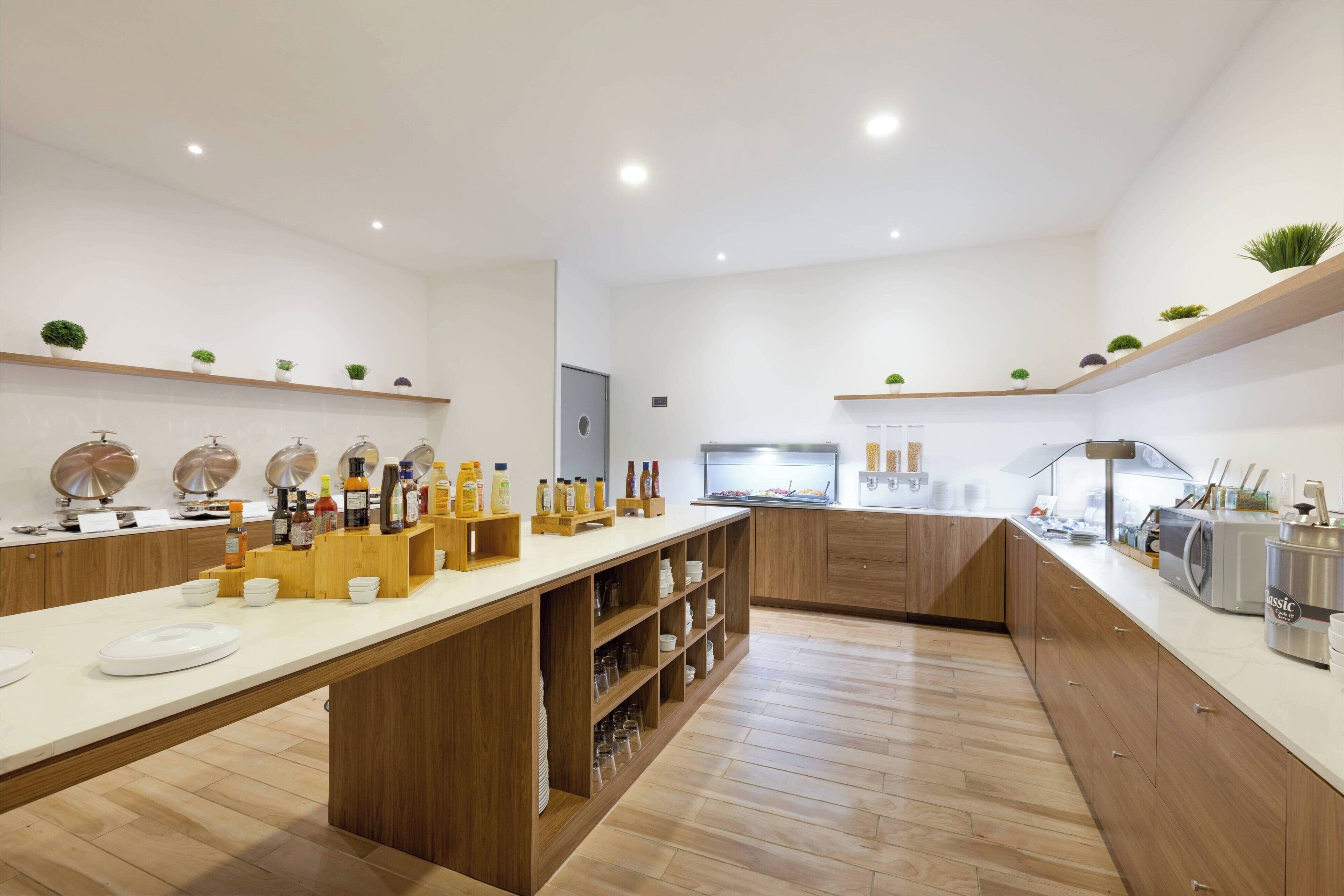 Une cuisine moderne avec des meubles en bois, un long plan de travail et divers appareils de cuisine.