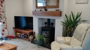 Ein Wohnzimmer mit Fernseher, Kamin, Sofa und Couchtisch.