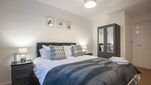 Un dormitorio ordenado con cama, mesitas de noche, armario y decoración en la pared.