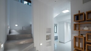 A modern interior with a staircase, white walls, and a wooden shelf unit. - Selene Villa With Private Pool and Sea View 96m (Tinos)