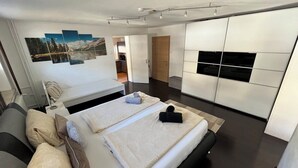 A modern hotel room with a bed, a sofa, and a large window. - Description (Schwendau)