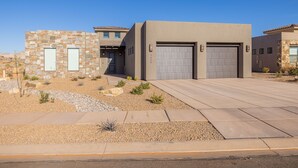 Une maison moderne à deux étages, dotée d’une façade en pierre, de deux portes de garage et d’une allée bien entretenue.
