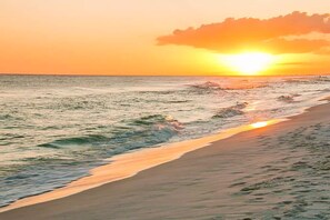 Une plage avec des vagues et un coucher de soleil.