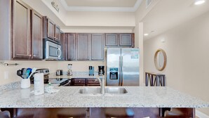 A kitchen with granite countertops, stainless steel appliances, and dark wood cabinets.