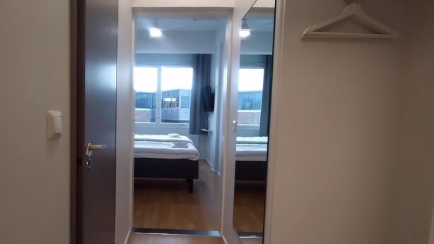 A hotel room with a bed, a bedside table, a hanging light, and a window. - Hotelli Kerava (Kerava)