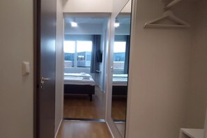 A hotel room with a bed, a bedside table, a hanging light, and a window. - Hotelli Kerava (Kerava)