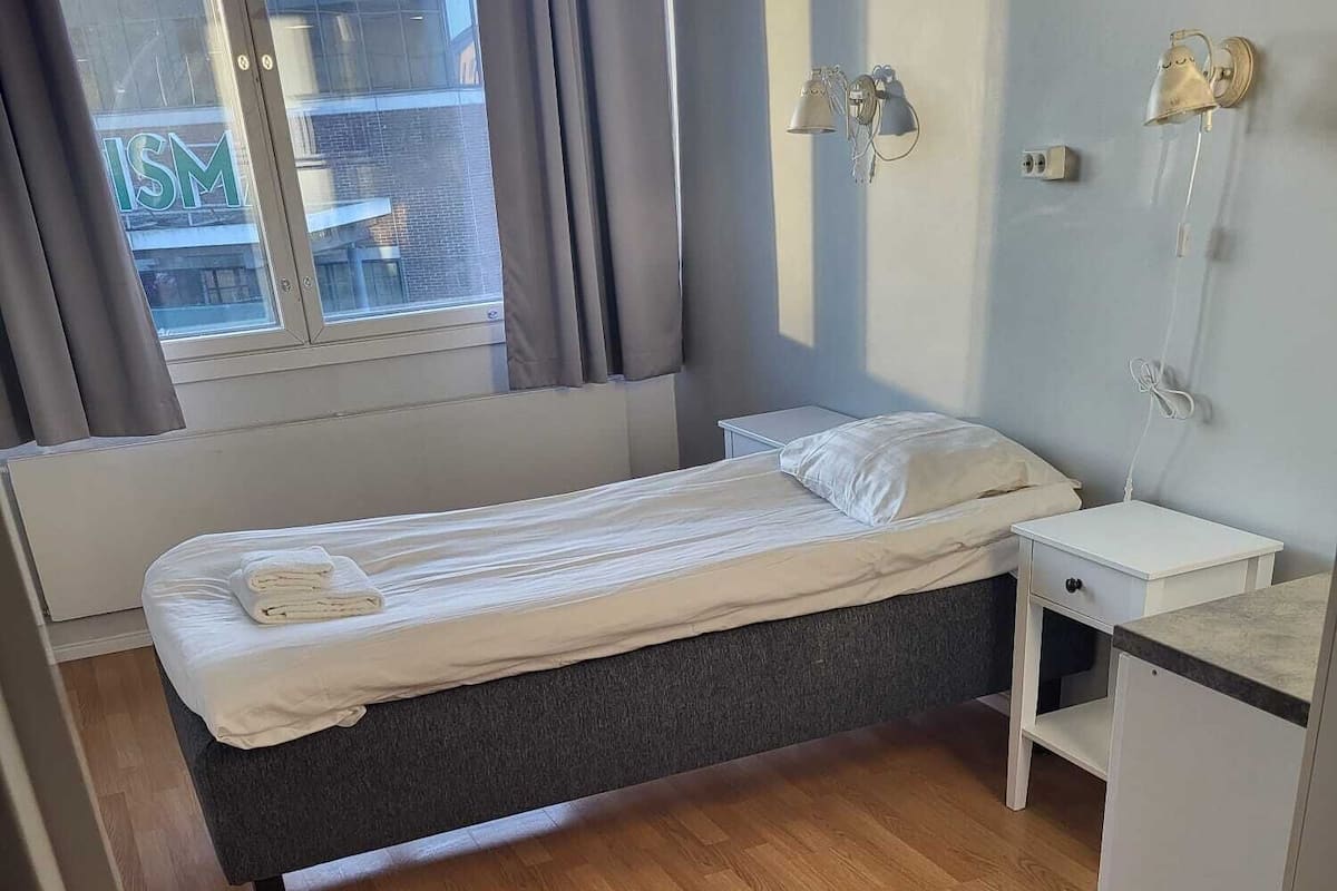 Un dormitorio pequeño y ordenado con cama, mesita de noche y escritorio.