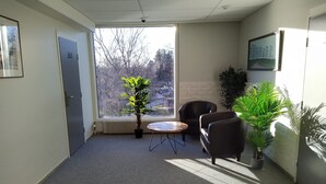 A small, well-lit room with a large window, a potted plant, a round table, and two chairs. - Hotelli Kerava (Kerava)