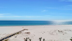 A beach with a wooden pier extending into the ocean, sandy dunes, and a clear blue sky. - Parking level!  Lazy river/Slide. New to the rental market!! (Orange Beach)