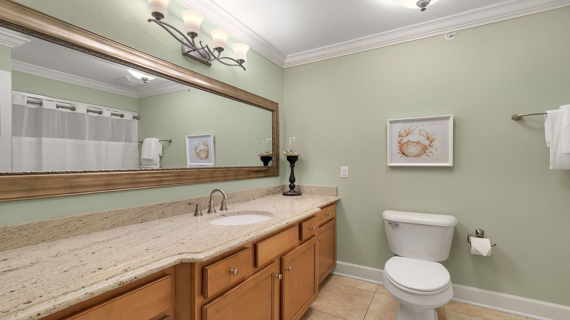 A bathroom with a vanity, sink, mirror, and toilet.