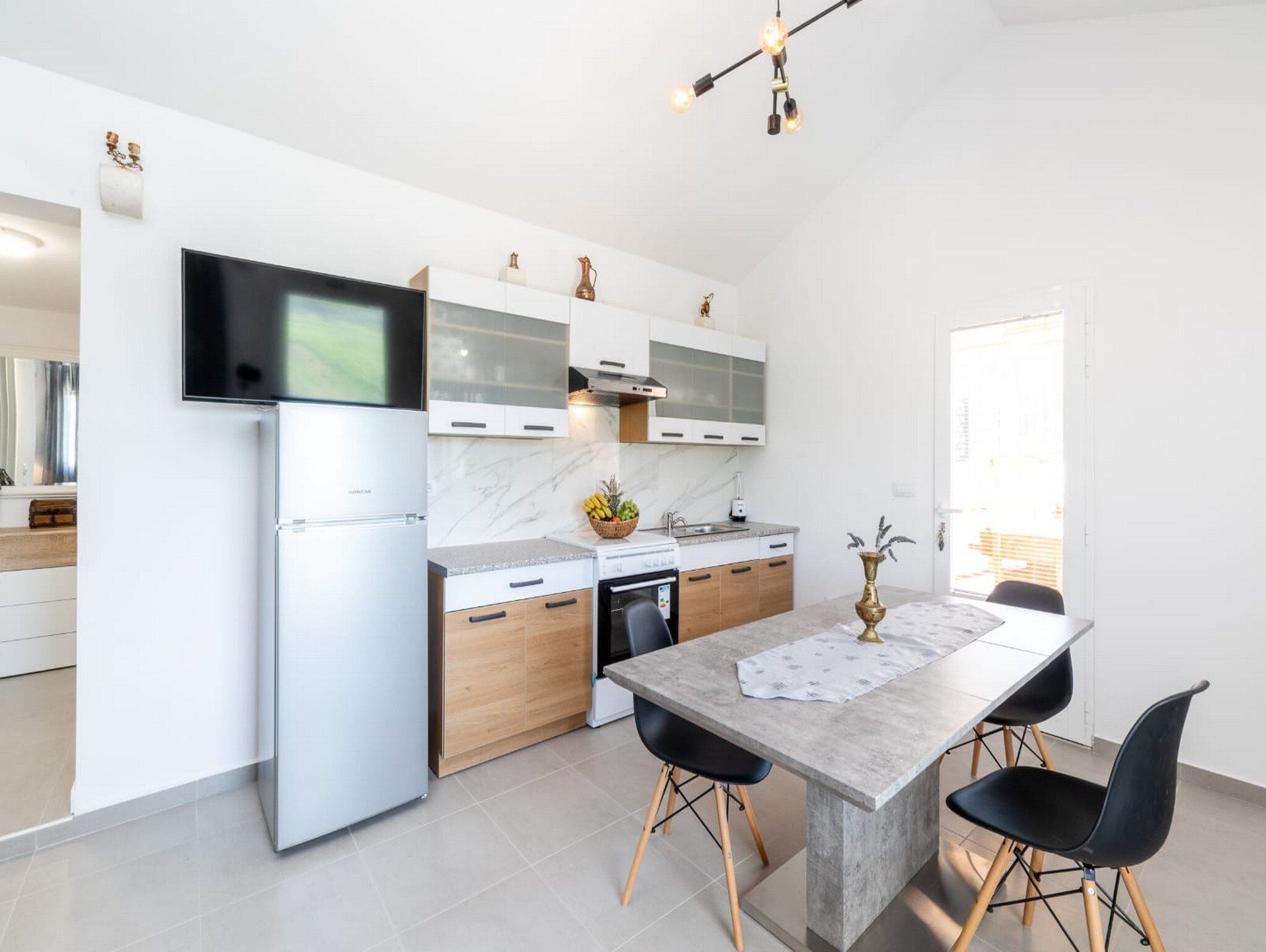 Eine moderne Küche mit Einbauofen, Kühlschrank und Essbereich mit Tisch und Stühlen.