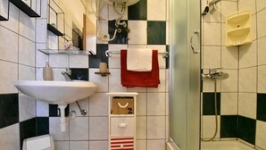 Une salle de bain équipée d’un lavabo, d’un miroir, d’un porte-serviettes, d’une douche et d’un meuble de rangement.