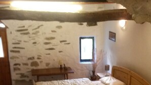 A bedroom with a wooden bed, a small bedside table, a nightstand, a window, and a stone wall. - Natursteinhaus Casa Angela, Terrassen, Garten, Meernähe, 140 m² (Dolcedo - Lecchiore)