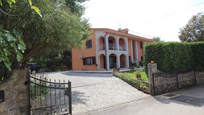 Un edificio de dos plantas con un patio central, una entrada protegida por un portón y un vehículo estacionado afuera.