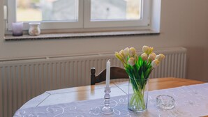 Een tafel met een glazen vaas vol tulpen, een kaars en een heldere glazen kandelaar.