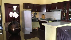 A kitchen with dark wooden cabinets, a white refrigerator, a microwave, and a stove. There is a vase with flowers on the counter.