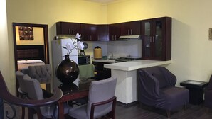 A compact living space with a dining area, a kitchen with dark wooden cabinets, a central island, and a small seating area.