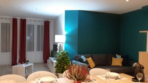 Un salon moderne comprenant un coin repas, un ensemble de canapés, une machine à café et une plante en pot.