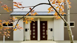 A building with a symmetrical facade, two prominent doors, and a small step leading to the entrance. - Villars Chalet (Hakuba)