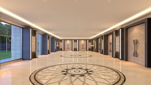 A modern hotel lobby with a central circular floor design, recessed lighting, and large doors with decorative panels. - Lemon Tree Premier Vijayawada (Vijayawada)