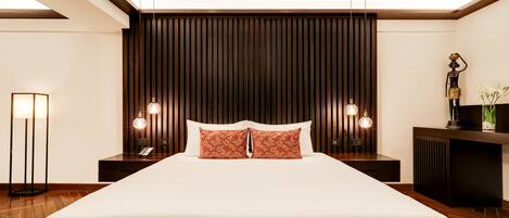 A neatly made bed with white linens and two decorative pillows, flanked by wooden headboards and nightstands with lamps.