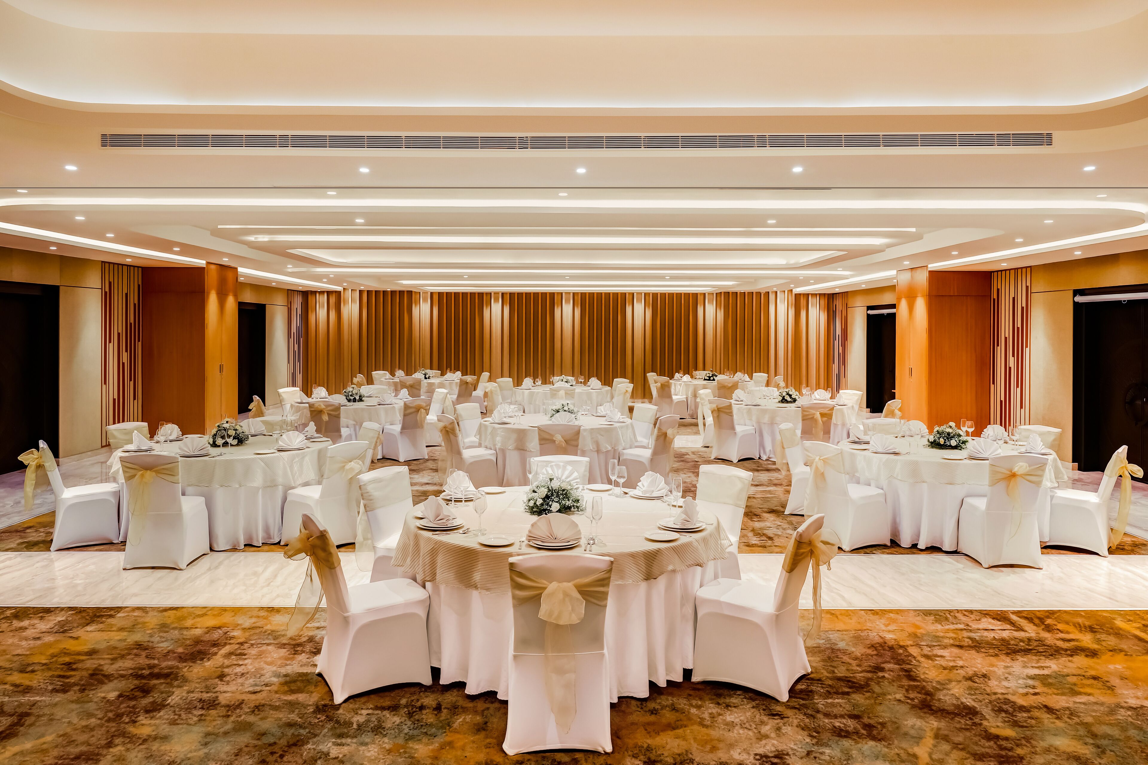 A large banquet hall with round tables and white chairs, arranged for a formal event.