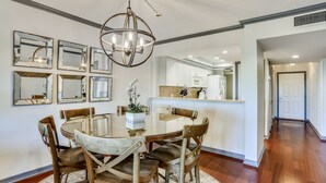 A dining area with a round table, six wooden chairs, and a chandelier. - Land's End 204 building 11 Beach Front|Close to pool|Amazing View (Treasure Island)