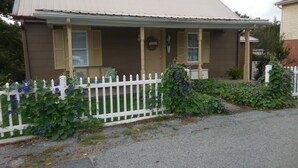 A two-story building with a brown facade and a white picket fence. - BACK TO THE 50'S GUEST HOUSE (Princeton, WV 24739)