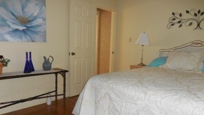 A bedroom with a bed, a nightstand, a lamp, a dresser, and a painting on the wall. - BACK TO THE 50'S GUEST HOUSE (Princeton, WV 24739)