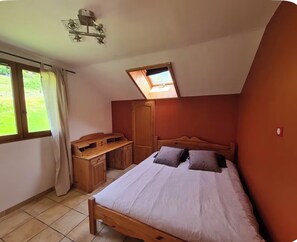 A bedroom with a bed, a desk, a wardrobe, and a skylight.
