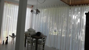 A dining area with a table and chairs, a chandelier, and sheer curtains.